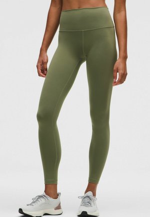 Leggings a vita alta verde oliva con una texture liscia e elastica e cuciture minime. Abbinati a scarpe sportive grigio chiaro con dettagli in mesh.