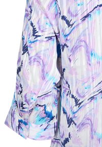 Blouse à manches longues avec manches retroussées, présentant un motif abstrait pastel dans des tons de violet, bleu et noir sur fond blanc.