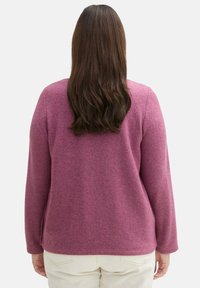 Pull-over en laine rose à manches longues, coupe décontractée et encolure ronde simple ; présente une texture douce avec des nuances subtiles partout.