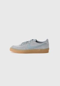 Baskets en suède gris clair avec une semelle en caoutchouc gomme et des coutures texturées, ornées d'un logo Nike bleu doux sur le côté.