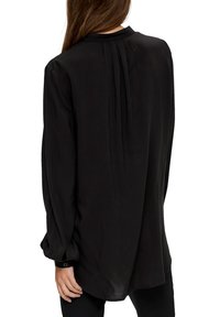 Zwarte blouse met lange mouwen van zachte stof, met een geplooide achterkant, knoopmanchetten en een afgeronde kraag in een ontspannen pasvorm.