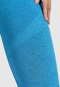 Leggings blu con una texture liscia, caratterizzati da un motivo melange e una cintura elastica per comfort e flessibilità.