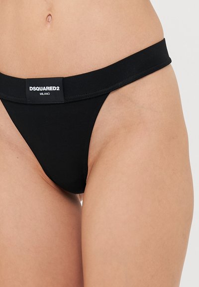 Black thong underwear with a wide elastic waistband featuring a logo tag. Smooth fabric with no visible patterns or embellishments.