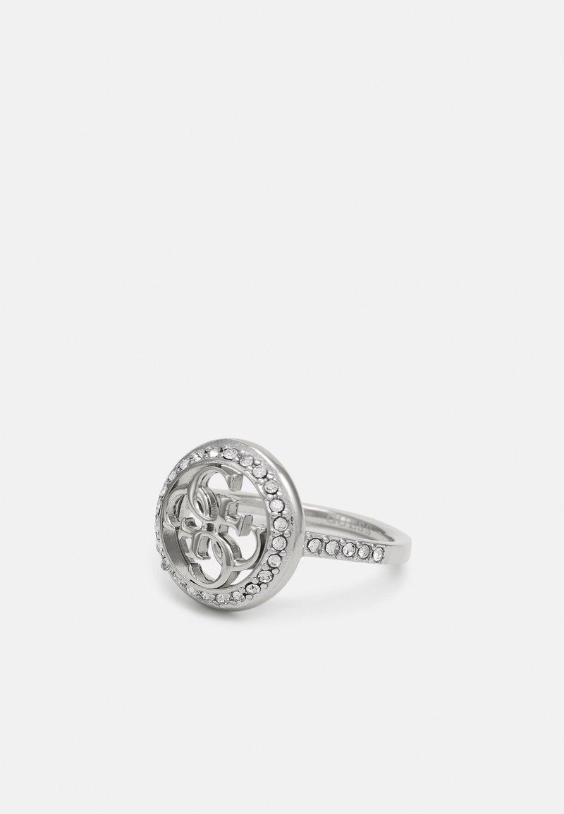Silverring med ett cirkulärt mönster, sammanflätade bokstäver, omgiven av en band av små klara stenar längs ringens skaft.