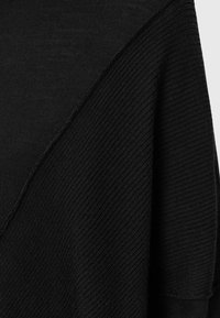 Maglione nero in maglia con design diagonale, caratterizzato da una texture a coste su un lato e una finitura liscia sull'altro. Cuciture e bordi ben rifiniti.