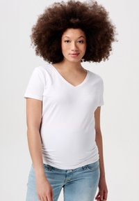 Witte korte mouwen v-hals t-shirt van zachte stof, met een aansluitend design, gedragen met lichtblauwe versleten jeans, wat de casual look benadrukt.