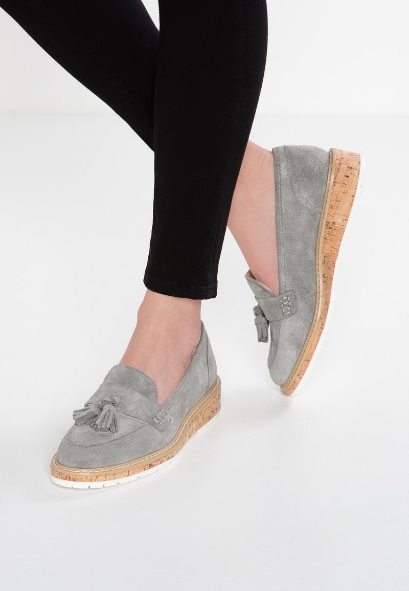 Chaussures en daim gris à enfiler avec un détail pompon, dotées d'un talon compensé en liège et d'une semelle en caoutchouc blanche.