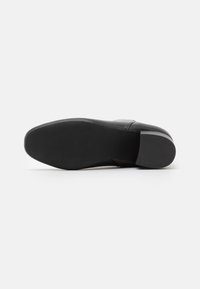 Suela de zapato de cuero negro con una puntera ligeramente redondeada. La parte inferior presenta un agarre de goma texturizada para mayor tracción. Diseño minimalista.