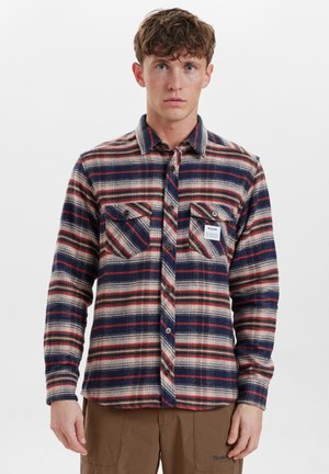 Camisa de franela a cuadros en rojo, marino y beige con botones en la parte delantera, dos bolsillos en el pecho y una etiqueta en el bolsillo izquierdo. Material de algodón, corte relajado.