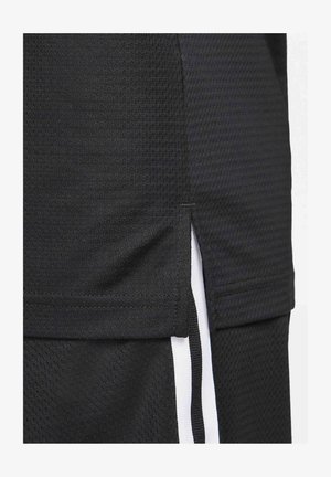 Maglia sportiva nera realizzata in un tessuto testurizzato, con orlo corto e spacchi laterali, e strisce bianche decorative lungo i lati.
