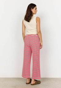 Un haut sans manches crème associé à un pantalon large à rayures rouges et blanches. Le pantalon a une coupe décontractée et est fabriqué dans un tissu léger.