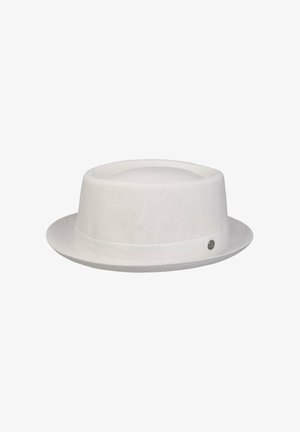 White linen pork pie hat with narrow brim and round metal brand emblem on the side.