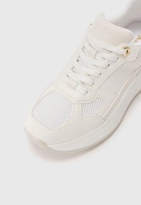Sneaker bianco con tomaia in pelle e mesh, chiusura con lacci e sottili accenti dorati. Suola spessa e design della punta rotonda per il massimo comfort.