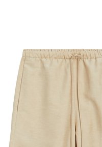 Pantalon beige avec taille élastique, poches latérales et cordon de serrage à l'avant.