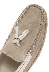 Zamszowe loafersy w jasnym beżu, z skórzanymi frędzlami, białym przeszyciem i podeszwą z juty w stylu espadryli. Okrągły kształt noska.