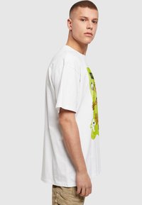 Balts kokvilnas T-krekls ar krāsainu grafisku apdrukājumu ar multfilmu varoņiem uz priekšpuses. Dizainā ir zaļi un brūni akcenti.