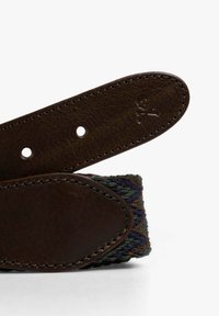 Cinturón trenzado con un extremo de cuero marrón oscuro, acentuado con un pequeño logo de calavera y tejido multicolor en tonos tierra.