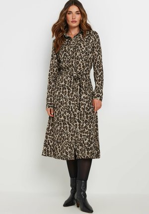 Vestito camicia con stampa leopardata in beige e marrone, maniche lunghe, vita alta con cintura, silhouette a trapezio, abbinato a stivali neri con tacco.