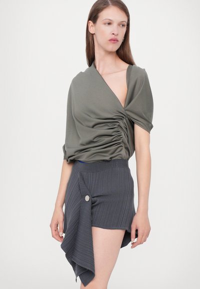 Olivengrøn, sammensnøring top med korte ærmer, parret med grå ribbede shorts med en draperet design og en sidelampe detalje.
