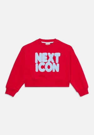 Punane pikkade varrukatega dressipluus ja sinine tekstuuriga kiri "NEXT ICON" esiküljel valgel taustal.