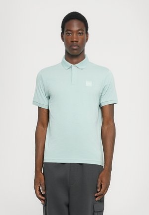 Light green polo shirt made of soft fabric, featuring a classic collar, short sleeves, and a small logo patch on the left chest.