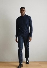 Navy knitted sweater with a crew neckline, paired with navy trousers and black leather shoes. Minimalistic design, smooth texture.