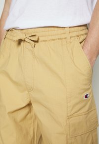 Beiga cargoshorts med elastisk midja och justerbar dragsko. Har sidofickor och en liten logotyp i sidofickan.