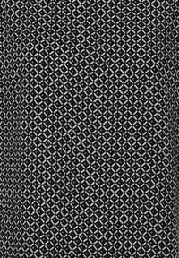 Schwarzer Stoff mit einem geometrischen weißen Muster aus ineinandergreifenden Rauten und Kreuzen, ergänzt durch kleine kreisförmige Akzente im Design.