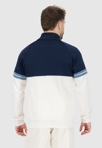 Sweatshirt pour homme en marine et blanc. Il présente un col montant, un design sportif et des accents de rayures bleu clair sur les manches. Tissu doux.