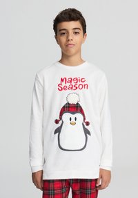 Sweatshirt bianco con una grafica di un pinguino che indossa un cappello a scacchi rossi, con "Magic Season" in testo rosso sopra. Materiale in morbido pile.