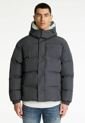 Doudoune noire avec un col haut et une capuche réglable ; présente des panneaux cousus et des poignets élastiques, portée par-dessus un sweat à capuche gris clair.