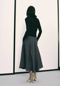 Czarny dopasowany sweter, szara spódnica w kształcie litery A i buty na wysokim obcasie w wężowy wzór. Gładkie tekstury na minimalistycznym tle.