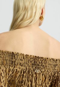 Bruine luipaardprint off-shoulder top met gathered elastische halslijn en een klein metallic logo detail. Glad, lichtgewicht stof.