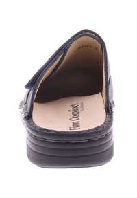 Marineblauwe instap loafer met een gevoerde beige binnenzool gelabeld "Finn Comfort," met een textuur van de zool en gedetailleerde stiksels rondom de randen.