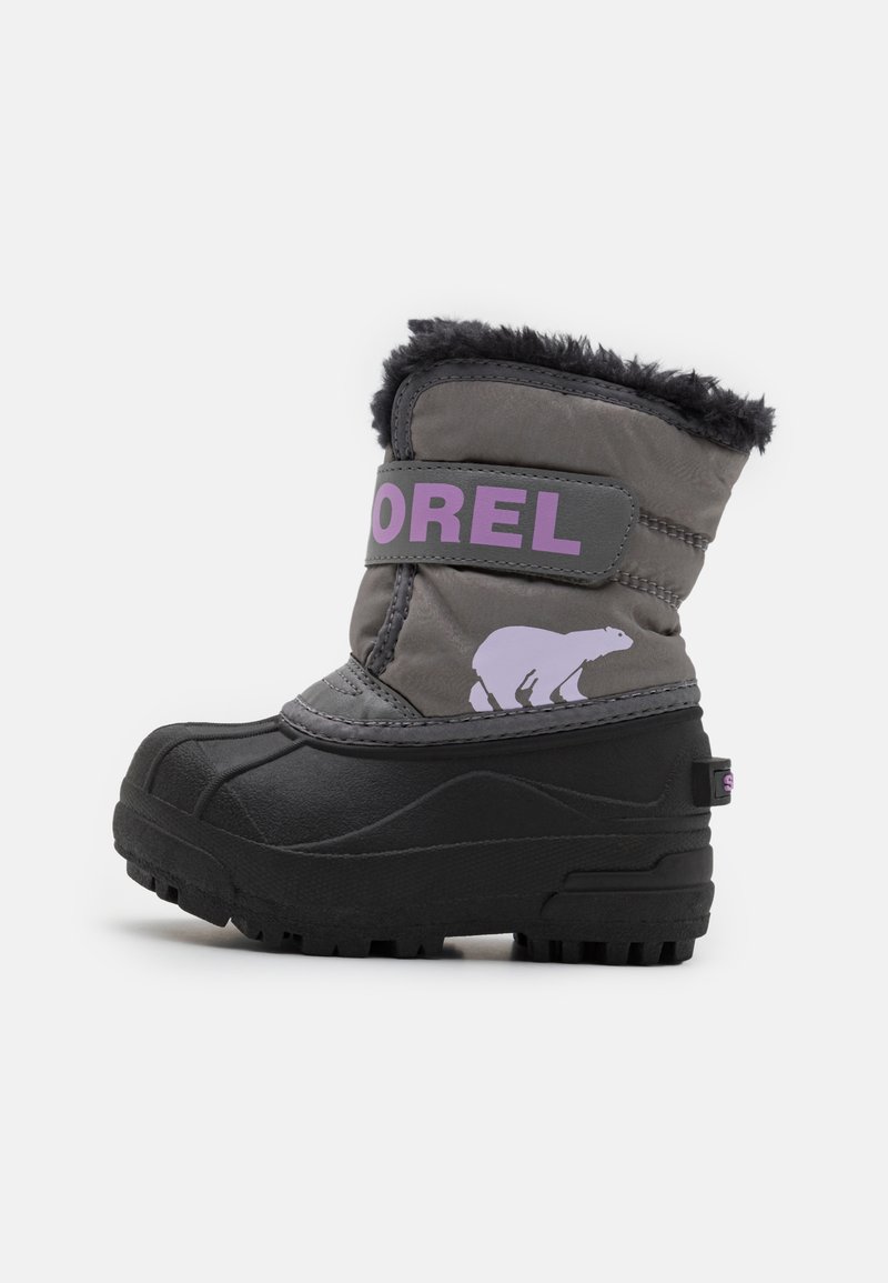 Bota de invierno gris con suela de goma negra texturizada, borde de piel sintética negra, correa con logo morado y gráfico de un oso polar en el lateral.