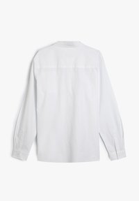 Camisa blanca de manga larga con cuello clásico, puños abotonados y una textura suave. La parte posterior presenta una costura en el yugo y no hay patrones visibles.