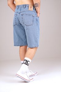 Denim shorts in light blue, featuring a straight cut, back pockets, and a leather patch; paired with white sneakers and thick white socks.