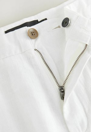 Pantaloni in lino bianco con zip, bottone marrone e cintura nera, caratterizzati da una texture liscia e una vestibilità su misura.
