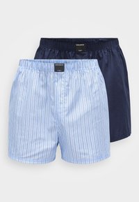 To par med herrebokser: en med blå og hvite vertikale striper, den andre i ensfarget mørk marineblå. Begge har elastiske midjebånd.