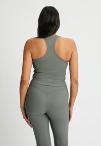 Gray ribbed tank top with a racerback design, paired with matching leggings. The fabric appears stretchy and form-fitting.
