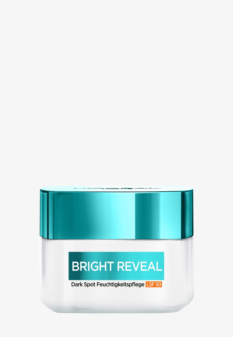 Bright Reveal mörkfläckscreme i en klar burk med ett turkosa lock. Etiketten har fet text; burken har en rundad design med en slät yta.