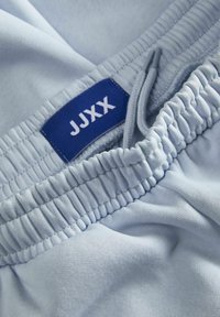 Lyseblå drawstring shorts lavet af blødt stof, med en elastisk talje og et mærket blåt label, der viser "JJXX."