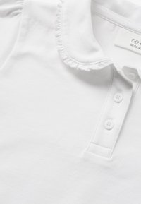 Weißes Poloshirt aus Baumwolle, mit einem Rüschenkragen, drei Knöpfen und glatter Textur. Einfaches und klassisches Design.