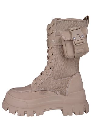 Beige hoge laars met een gestructureerde nylon bovenkant, dikke rubberen zool en een aangehechte zak aan de zijkant voor extra opbergruimte.