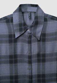 Camicia a quadri grigia scura e nera con colletto a punta e etichetta visibile all'interno del colletto.