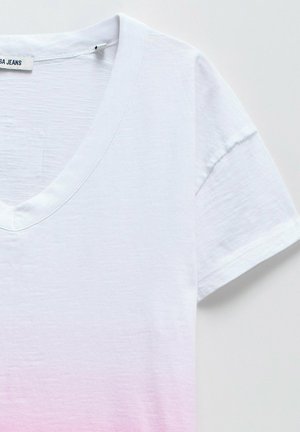 Camiseta blanca con escote en V y mangas cortas, que presenta un degradado de blanco a rosa claro. Tela suave y ligera con un acabado ligeramente texturizado.