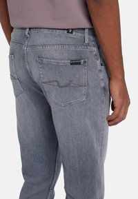 Lichtgrijze denim jeans met een regular fit, voorzien van achterzakken, subtiele stikseldetails en een merketiket op de tailleband.