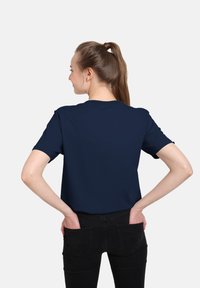Granatowa koszulka z krótkim rękawem, okrągłym dekoltem, luźnym krojem, miękką fakturą materiału i bez widocznych grafik czy wzorów.