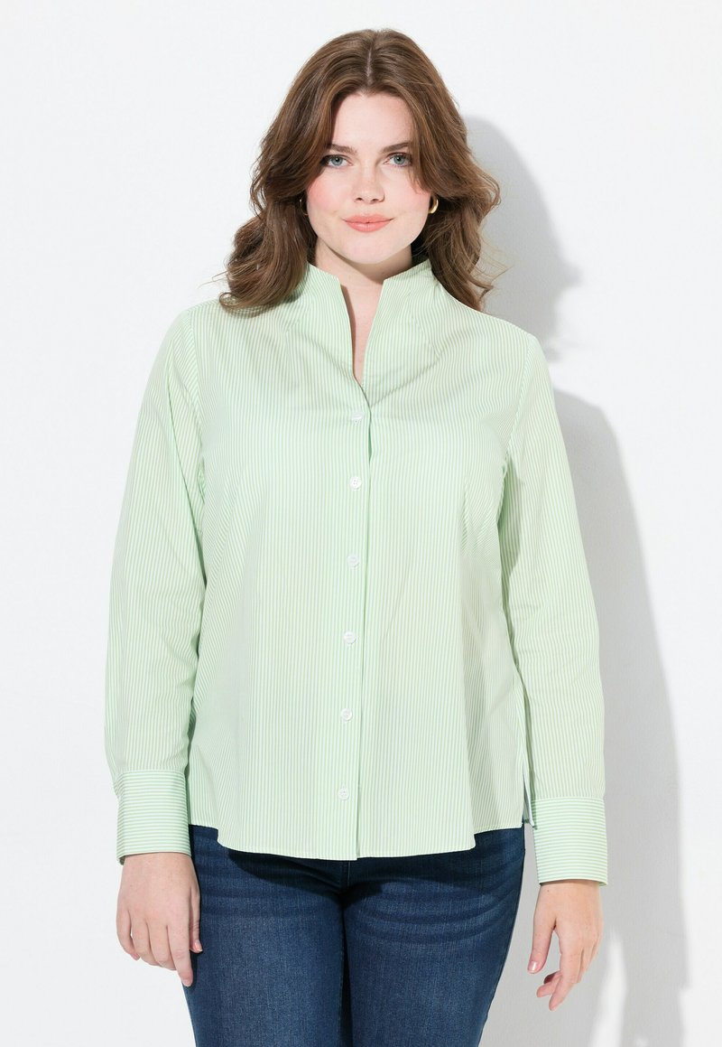 Lichtgroene button-up blouse met verticale witte strepen, voorzien van een staande kraag en lange mouwen, gecombineerd met donkerdenim jeans.