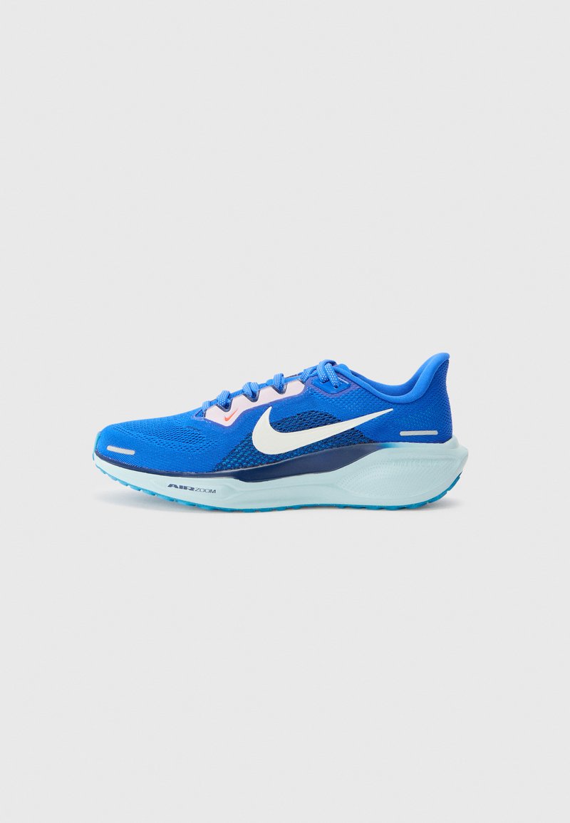 Blå løbesko med en åndbar mesh-overdel, hvid Nike swoosh, tekstureret mellemsål og lyseblå ydersål. Har snørebånd og accenter i pink.